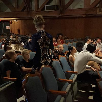 Dancers sit and chat in the seats of the 1938 Original Theatre, preparing to perform.