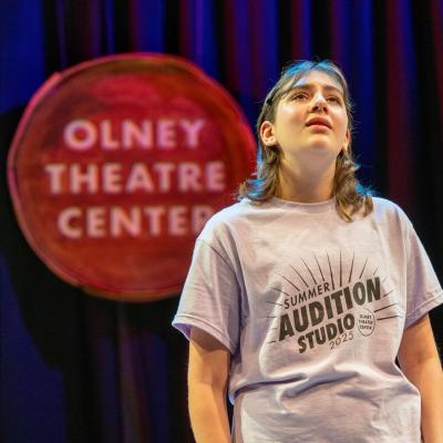 A high schooler, looking up, in the middle of singing a song